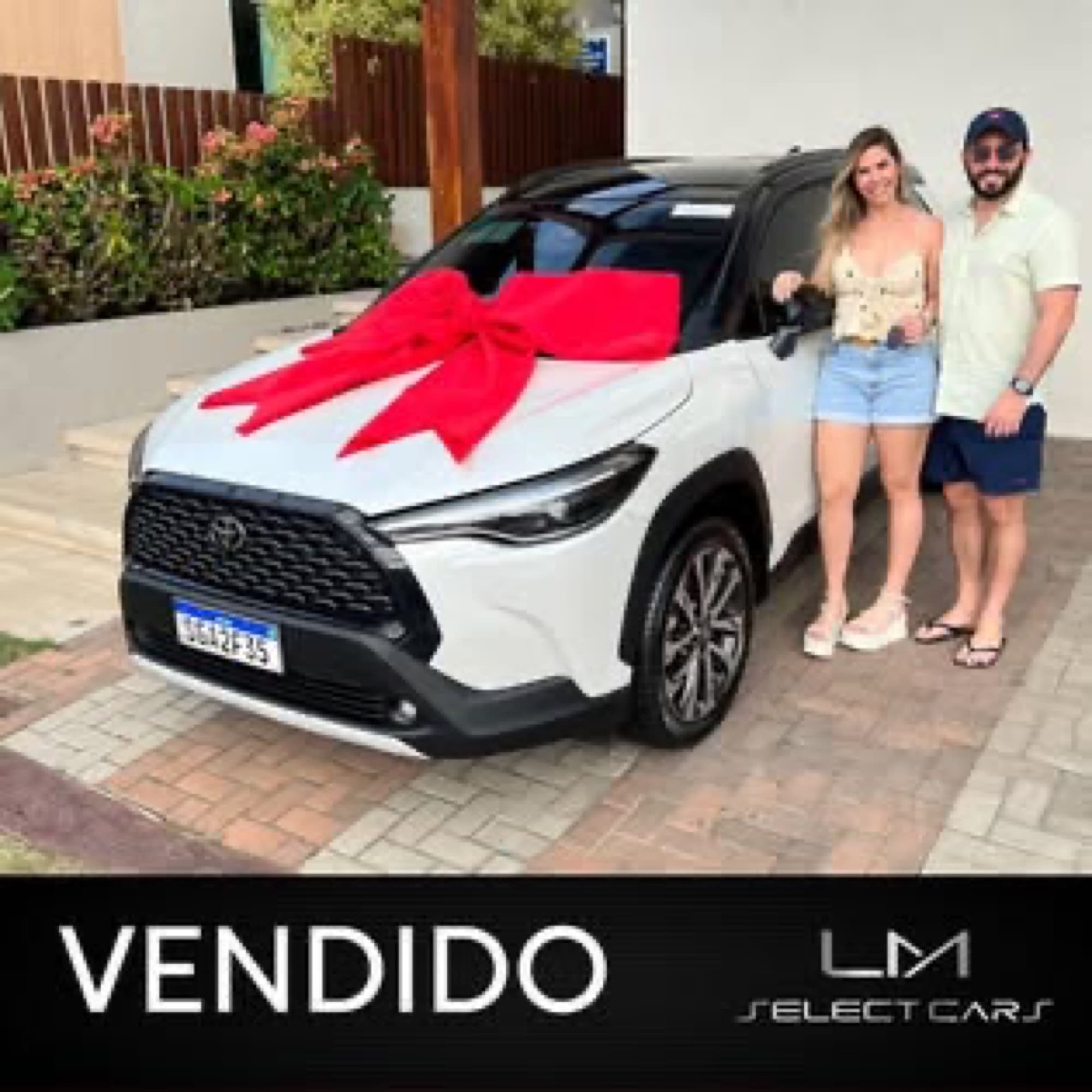 Casal recebendo Toyota Corolla Cross com laço vermelho