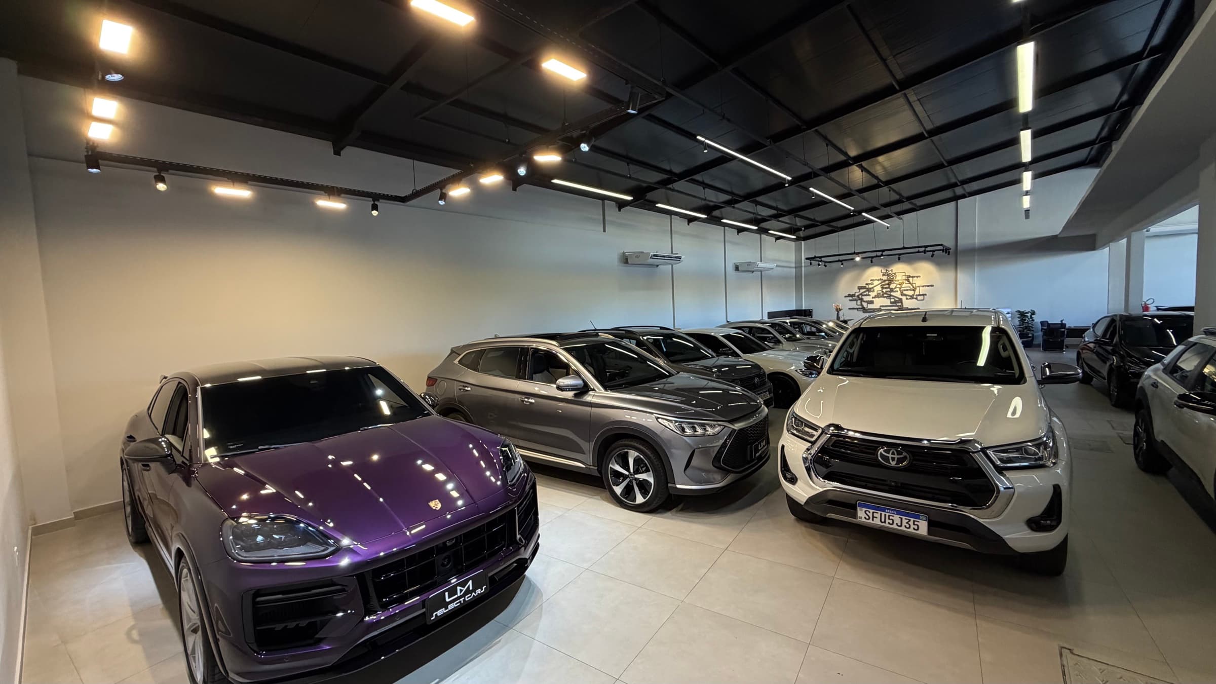 Porsche Cayenne roxo e Toyota Hilux no showroom LM