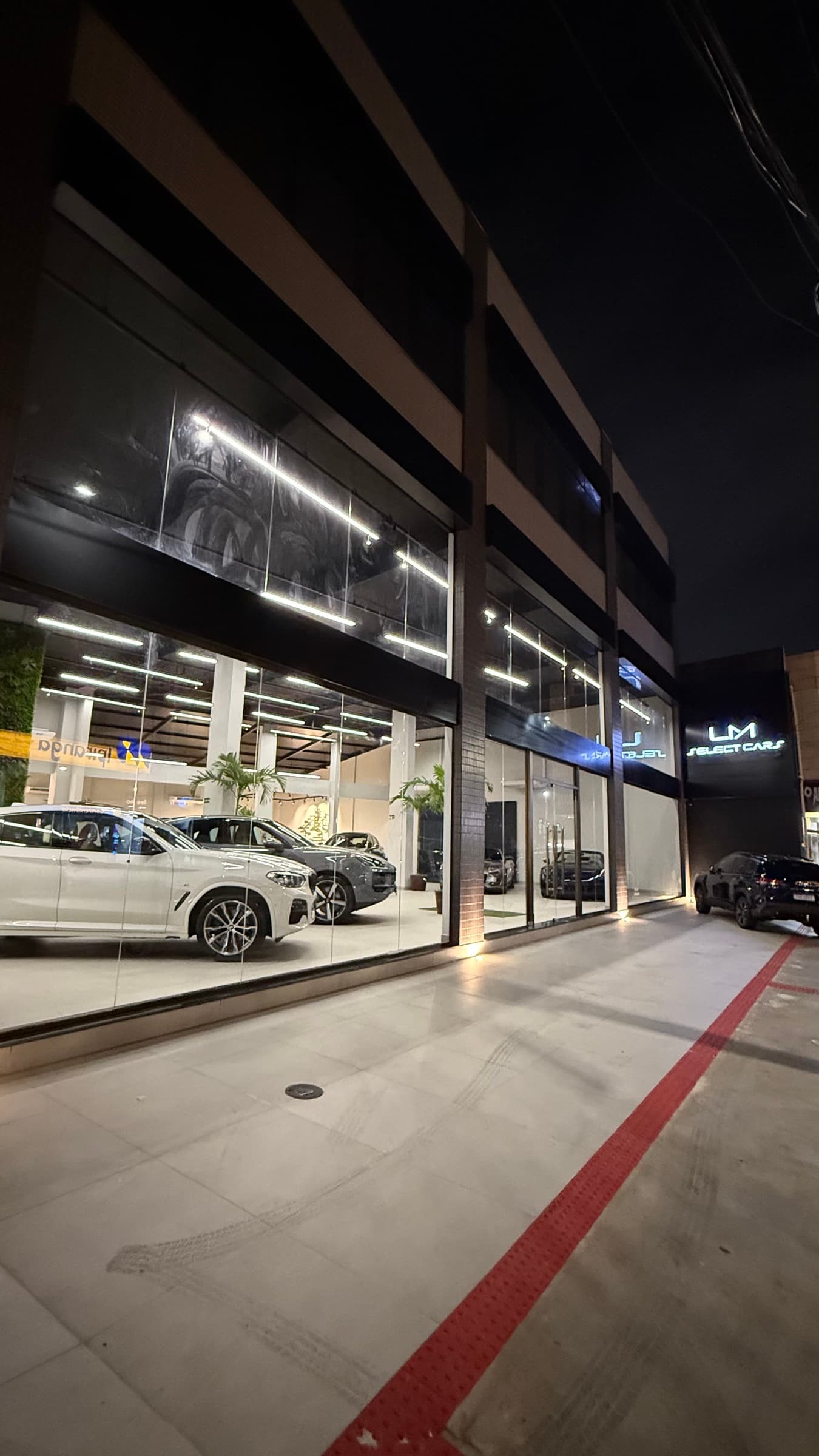Fachada da LM Select Cars à noite, showroom iluminado